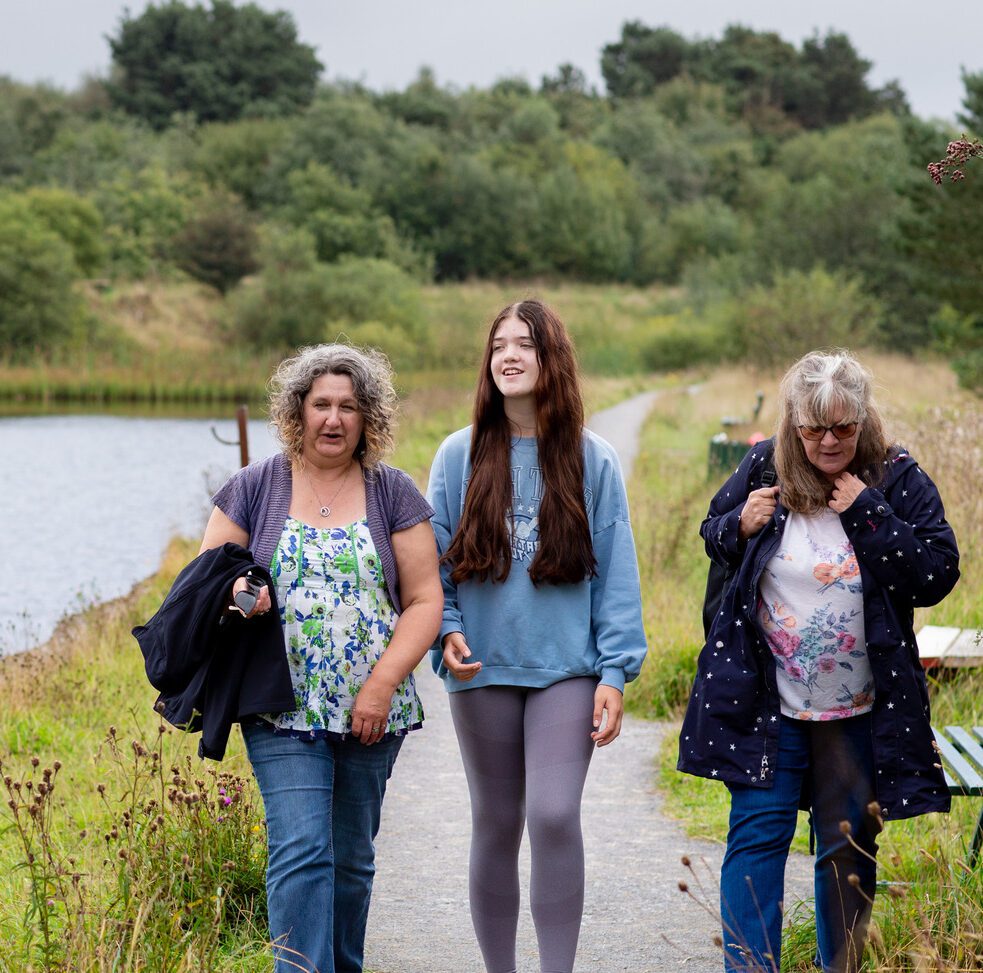 girl and two ladies walking by water